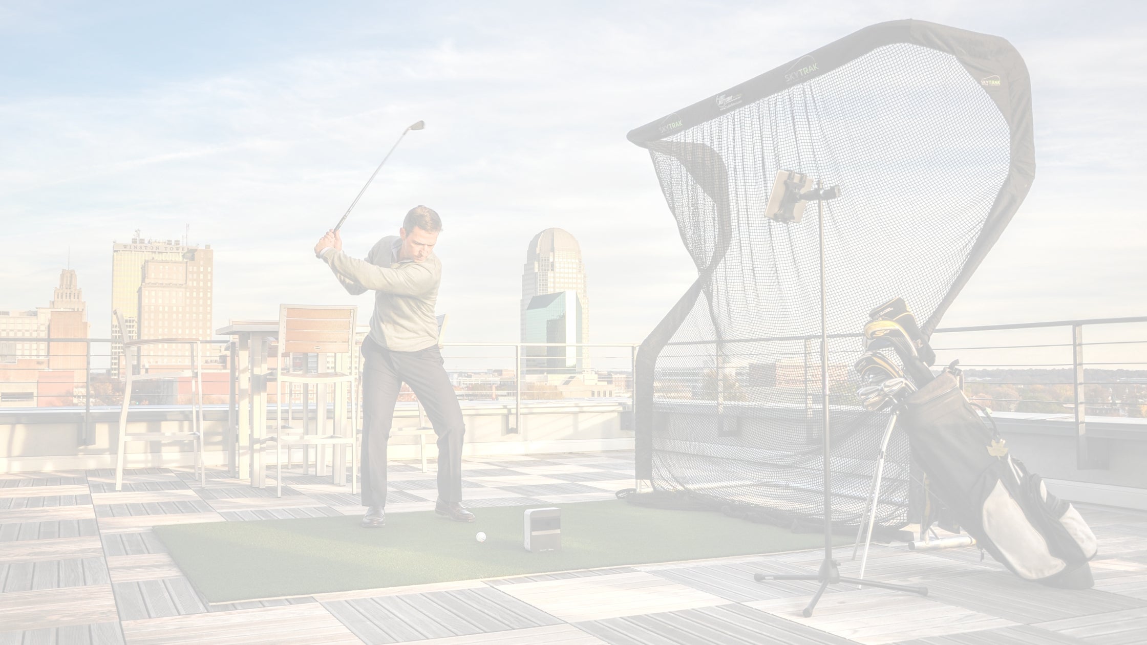 Golfer practicing on a rooftop with SkyTrak launch monitor and Net Return golf net